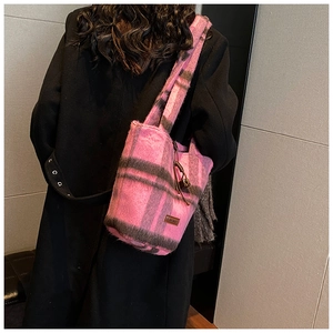 Detail view of pink and black plaid plush tote bag with brand leather tag and tassel