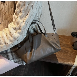 Detail of dark brown pleated PU leather handbag with elegant soft texture and strap