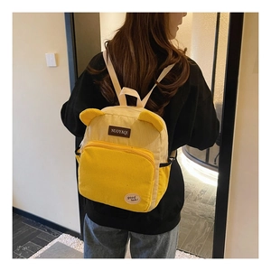 Detail view of a yellow corduroy backpack with cute 3D bear ears on a model's back