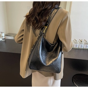Detail of black glossy vintage leather tote with adjustable wide strap and gold hardware