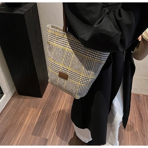 Detailed view of women's autumn plaid tote bag with brown leather straps and patch