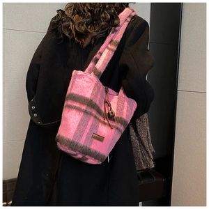 Detail of pink and brown checkered plush tote bag with brand logo and wooden bead accessory