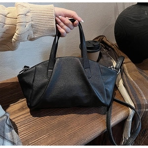 Detail of black pebbled PU leather tote with V-shaped pleated design and detachable strap
