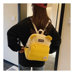 Close-up of yellow corduroy backpack with cute ear accents and embroidery detail