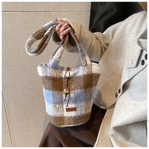 Macro detail of plush wool blend bucket bag with brown and blue plaid texture and drawstring