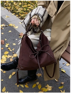 Deep brown large tote bag with matte suede texture and decorative bow in autumn setting