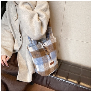 Detail of plush plaid tote bag with drawstring closure and decorative leather patch