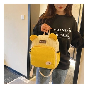 Detail of yellow and beige corduroy mini backpack with bear ears and branded leather label