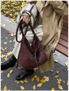 Macro detail of dark brown matte suede tote with decorative bow accent for autumn