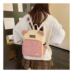 Detail of color-block corduroy backpack with cute bear ears worn by model in a modern room