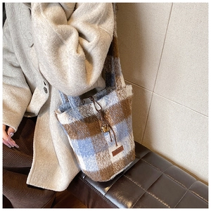 Detail shot of plush checkered bucket bag with leather tag and soft wool texture