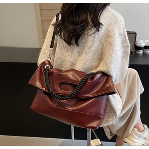 Detail of burgundy PU leather handbag with braided handle and adjustable shoulder strap