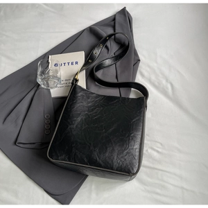 Vintage black faux leather tote bag with pleated texture and adjustable strap on a blazer