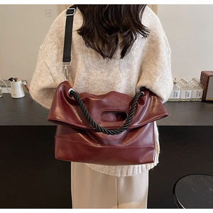 Macro view of burgundy PU leather crossbody bag with oval cutout handle and woven strap