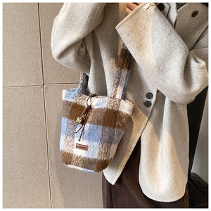 Detail of plush plaid bucket bag featuring blue and brown check pattern with drawstring