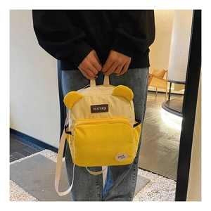 Detail of yellow corduroy backpack with cute bear ears and stylish patch design