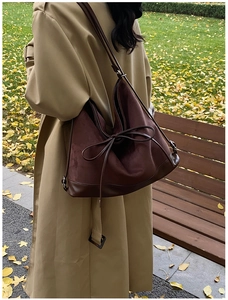 Detail of burgundy suede and brown leather tote bag with a stylish bow on a trench coat