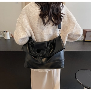 Detail of black faux leather tote featuring a thick twisted rope handle and wide strap