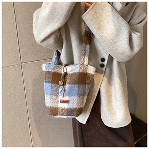 Detail view of plush textured bucket bag with blue and brown plaid pattern design