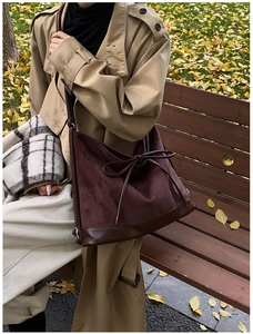 Detail of large dark brown suede tote bag with leather bow decoration in autumn park