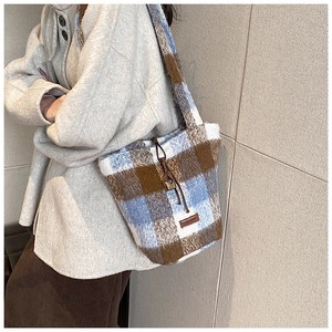 Detailed view of the checkered knit bucket bag with brown leather drawstring and logo tag