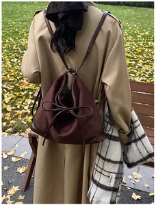 Macro detail of dark brown matte PU leather backpack with a bow knot in an autumn setting
