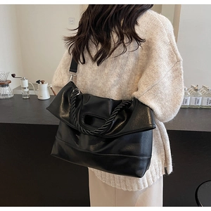 Detail of black soft PU leather tote bag with pleated texture and woven handle design