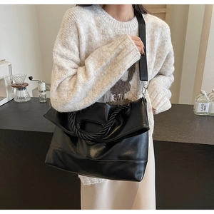 Detail of black PU leather tote with woven handle and adjustable wide nylon shoulder strap