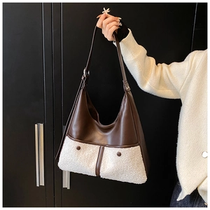Detail of the brown leather and cream faux shearling contrast on a large tote bag