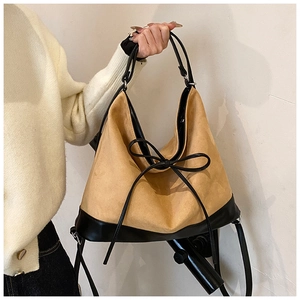 Detail of tan suede tote bag with black leather trim and decorative bow knot detail