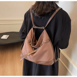 Detail eines braunen Vintage-Wildlederrucksacks mit dunklen Lederbesätzen und Messingösen