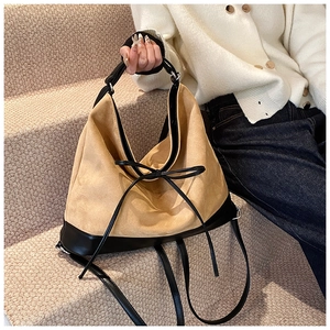 Detail of light brown matte leather hobo bag with black stitching and bow accent