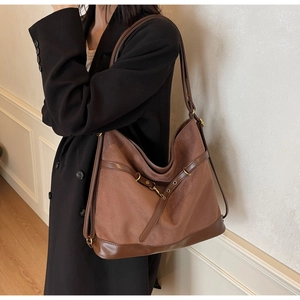Detailansicht einer braunen Vintage-Einkaufstasche mit Wildleder-Struktur und Metallschnalle am Gurt