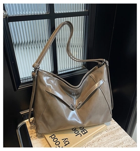 Détail du grand sac cabas en cuir beige avec coutures en V sur une surface en pierre