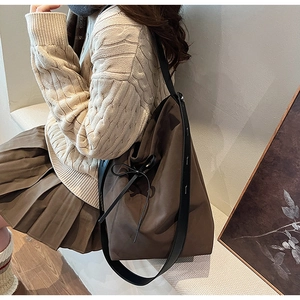Détail d'un grand sac cabas en daim marron avec nœud décoratif et bandoulière large