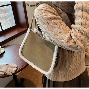 Close-up of khaki green suede shoulder bag with plush faux shearling trim on winter outfit