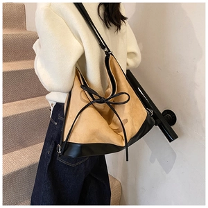 Detail of large tote bag showing khaki frosted texture with black leather trim and bow