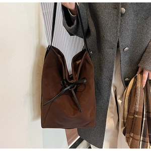 Détail du sac cabas en daim marron café avec nœud noir et bandoulière en cuir