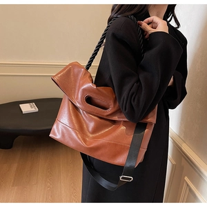Close-up of brown PU leather tote bag with oval handle and black braided shoulder strap