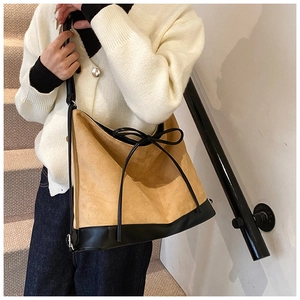 Detail shot of camel faux suede tote bag with black leather straps and bow drawstring