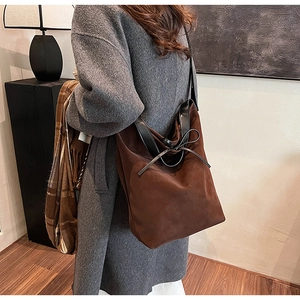 Détail du grand sac cabas en daim marron avec anses en cuir noir et nœud décoratif