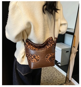Brown bucket bag with leopard print details shown on a model in a modern indoor setting