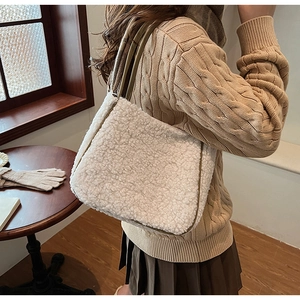 Close-up of a white faux shearling tote bag with olive green straps worn by a model