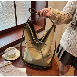 Détail du grand sac hobo en daim vert olive avec bandoulière en cuir marron au café