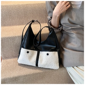 Detail of winter fashion hobo bag showing black PU leather and white fleece pocket contrast