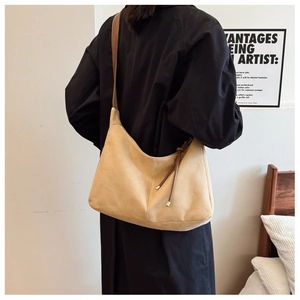 Detail of minimalist beige tote bag with brown leather strap and side tassel ornament