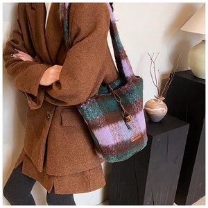 Detail of checkered plush tote bag featuring leather YAMANAI label and drawstring closure