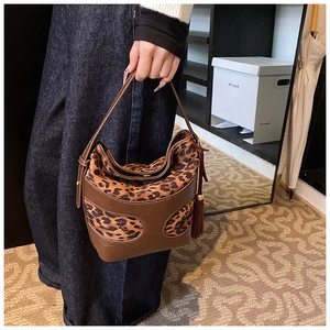 Detail shot of leopard print handbag with brown leather trim and stylish tassel accents