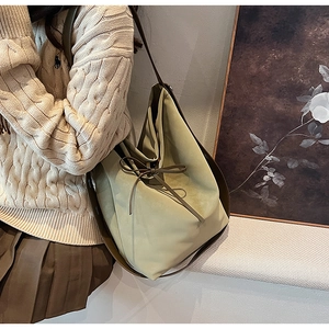 Détail du sac cabas en daim vert pistache avec nœud coulissant et bandoulière brune
