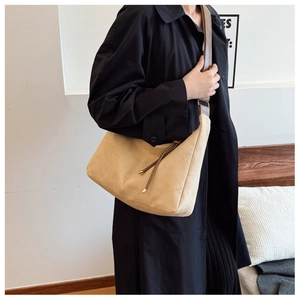 Macro detail of a beige matte faux suede tote bag with brown leather strap on model